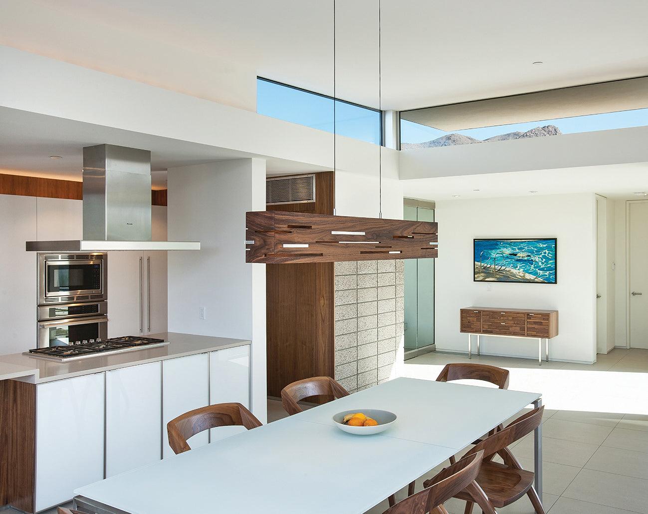 Aeris walnut linear pendant light hanging over a modern dining table
