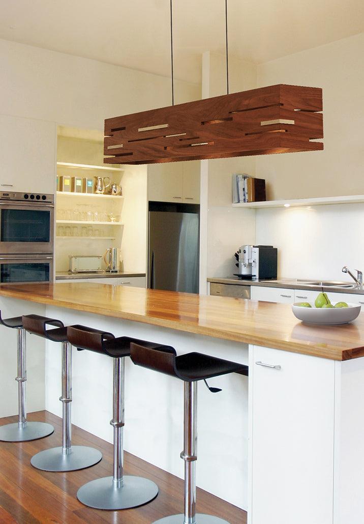 Aeris walnut linear pendant chandelier hanging over a modern kitchen island.