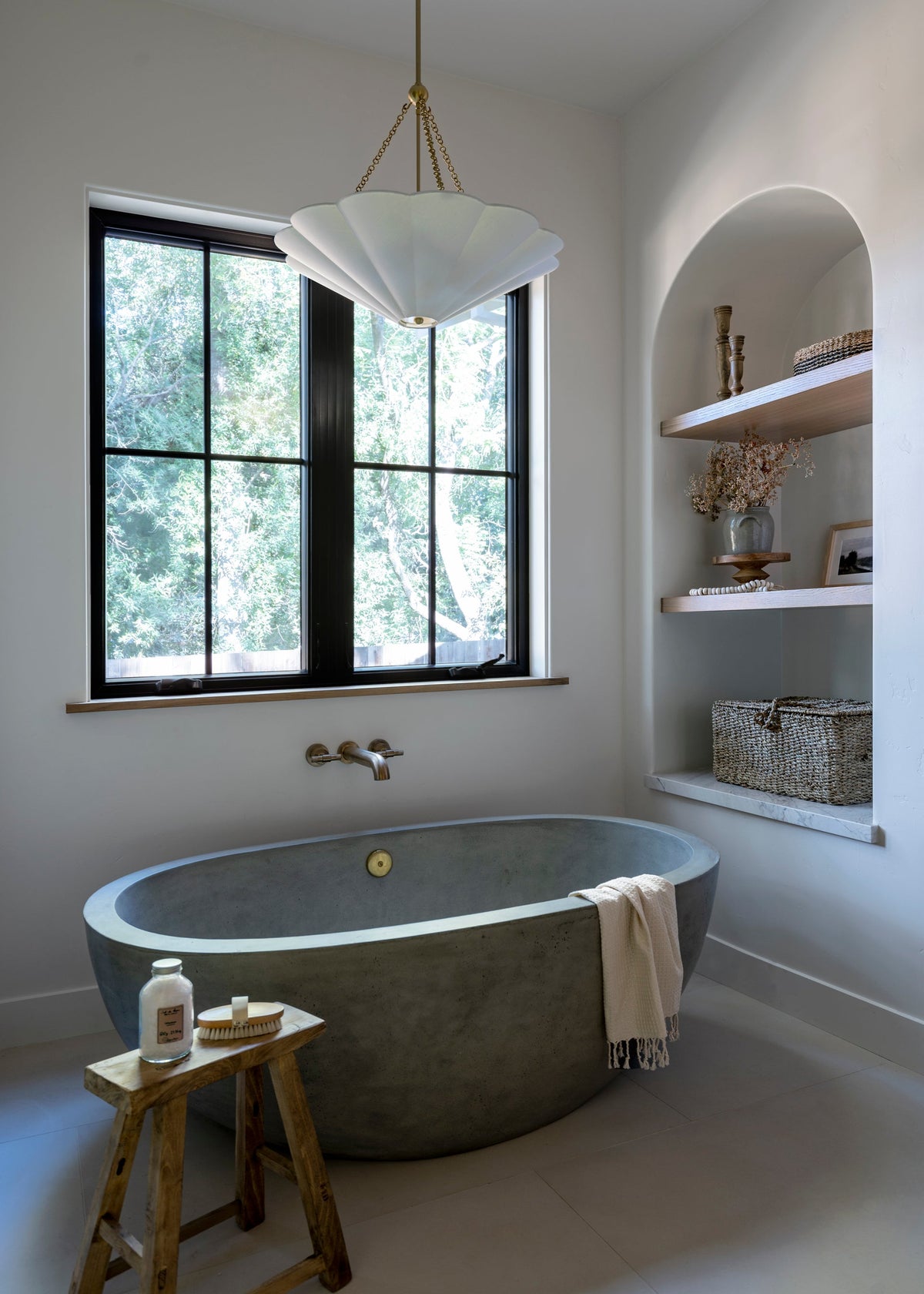 Alana white linen scalloped pendant light with aged brass chain hanging above a concrete bathtub