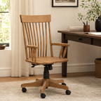 Albany wooden desk chair with a spindle back, armrests, and a wheeled swivel base next to a desk.