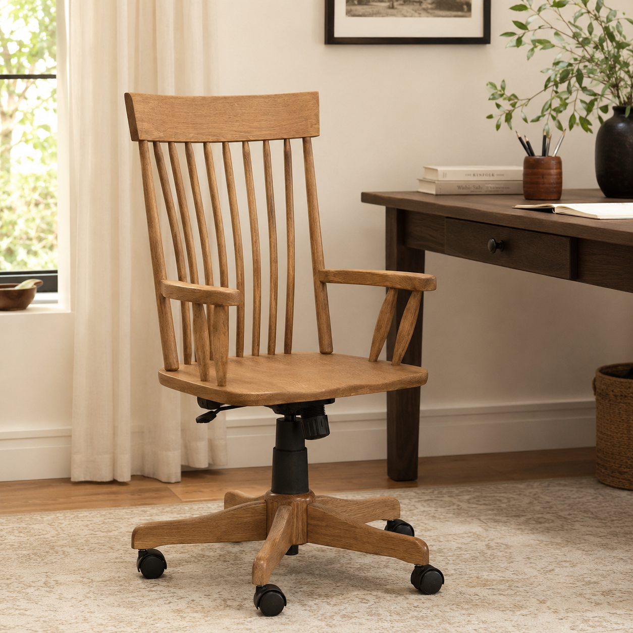 Albany wooden desk chair with a spindle back, armrests, and a wheeled swivel base next to a desk.