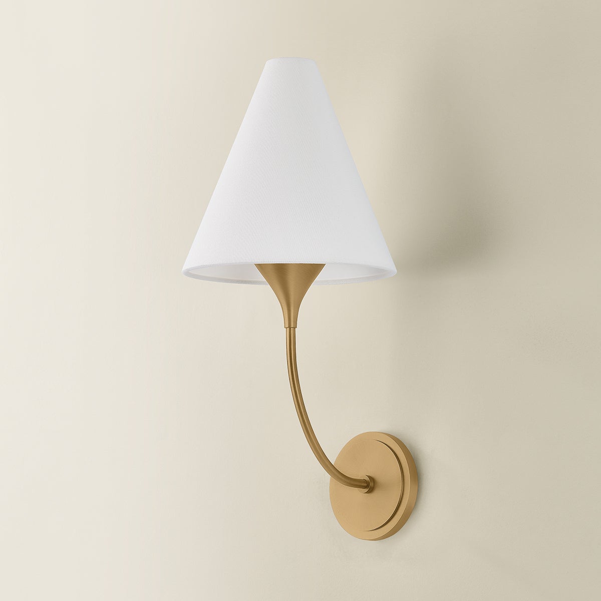 Evermore brass wall sconce with a curved arm and white linen shade.