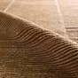 Bezem hand-knotted brown wool rug showing its textured, ribbed weave and folded corner.