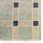 Cera Tiles hand-knotted wool rug with a sage green, beige, and blue geometric plaid pattern.