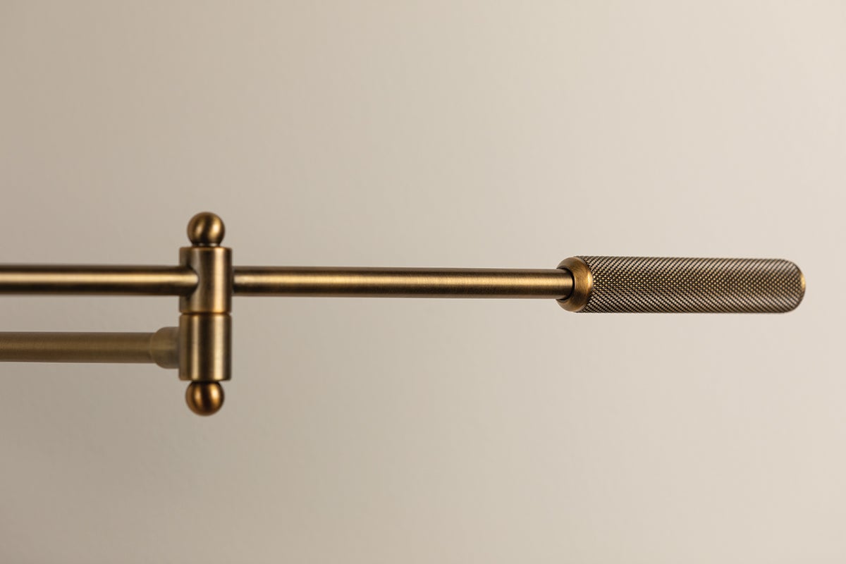 Patina brass adjustable arm of the Cannon wall lamp featuring a textured knurled handle.
