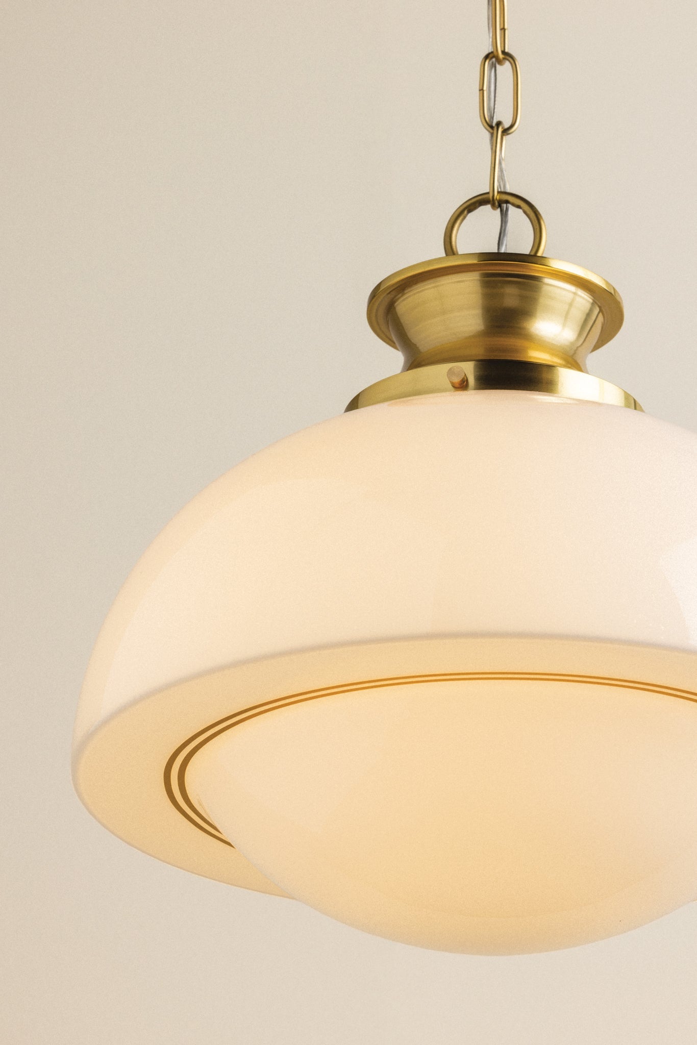 Celine mid-century pendant light with a domed opal glass shade, gold pinstripes, and brass hardware.