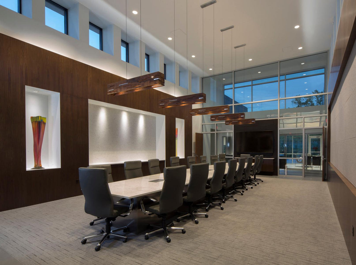 Aeris linear walnut pendant lights hanging over a modern conference room table