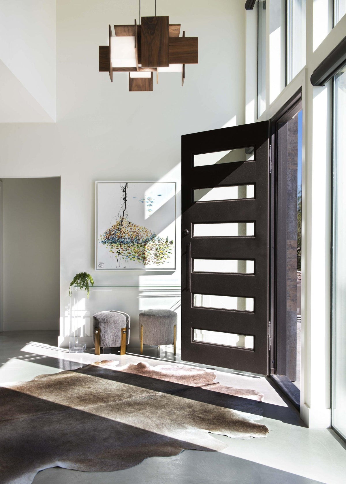 Muto walnut wood pendant chandelier hanging in a modern entryway with an open front door.