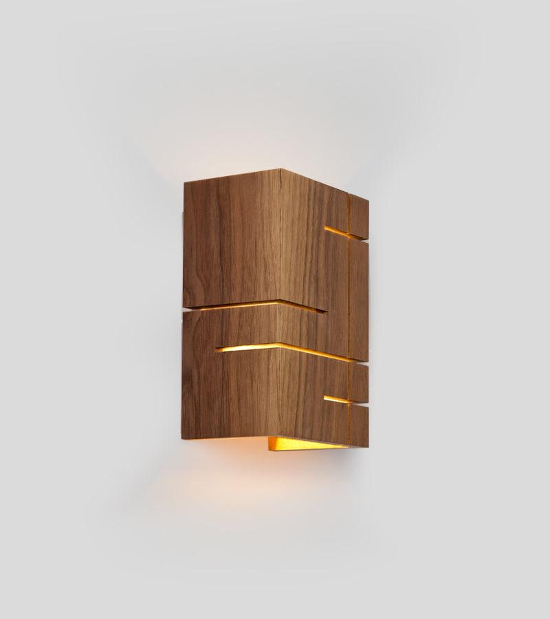 Claudo Sconce in solid walnut with geometric cutouts and warm LED light.