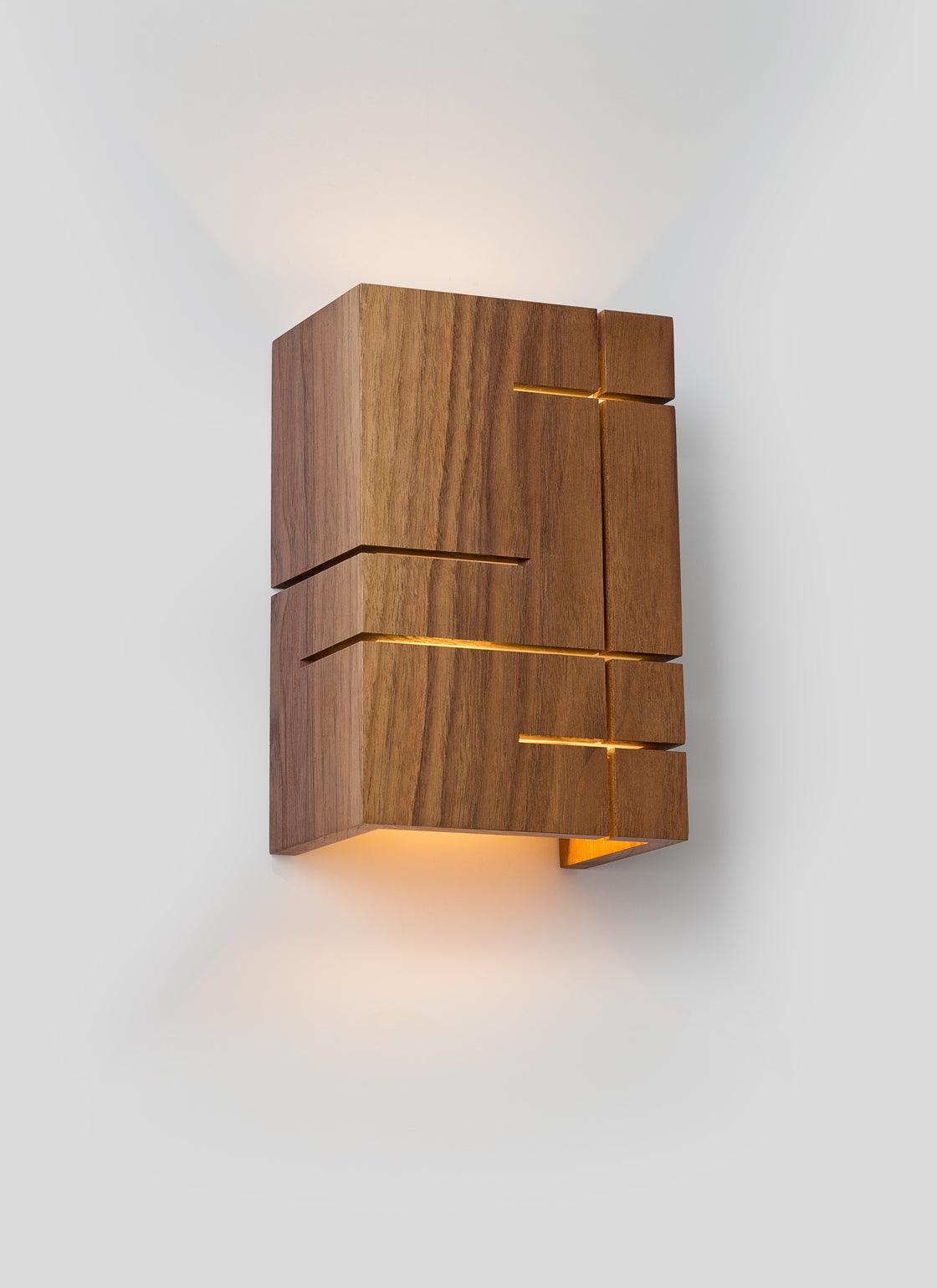 Claudo solid walnut wood sconce with geometric cutouts and warm LED light.