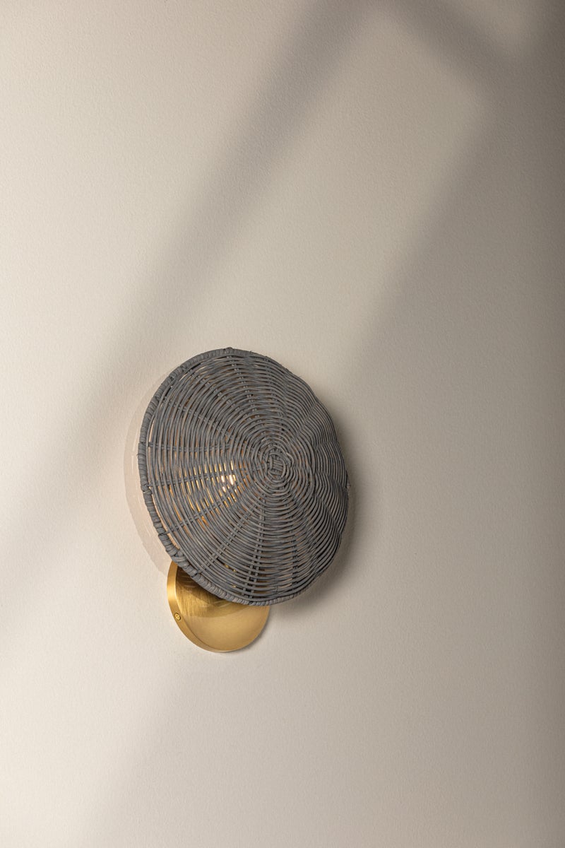 Destiny Wall Sconce with gray wicker shade and aged brass base on a neutral wall.