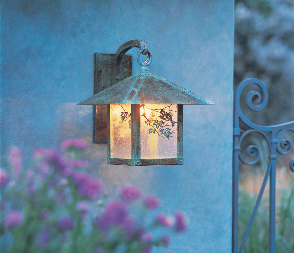 Evergreen Filigree wall mount lantern in verdigris patina with glowing gold white iridescent glass.