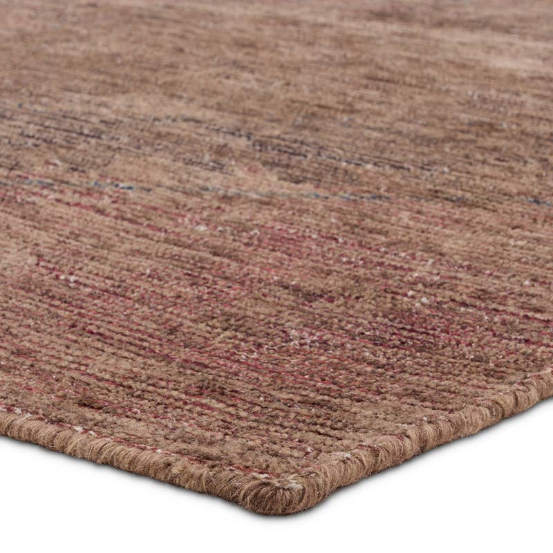 Elaida hand-woven jute and wool rug in textured brown, red, and blue tones.