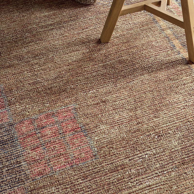 Elaida hand-woven jute and wool rug in textured brown with red and blue geometric accents.