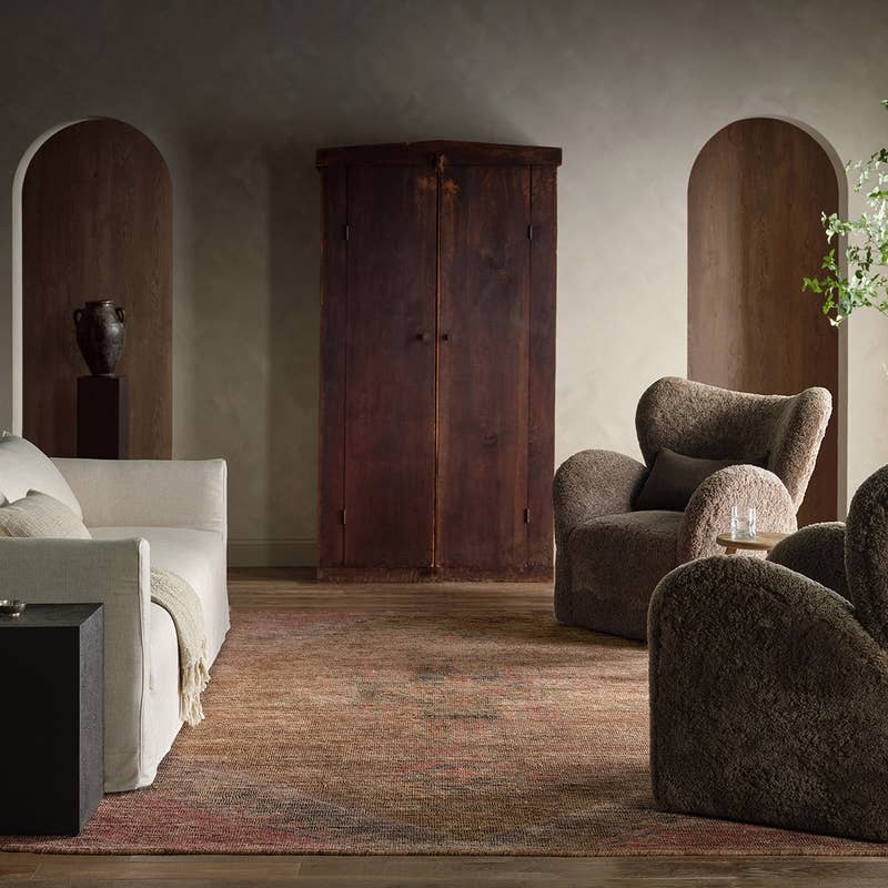 Elaida hand-woven jute blend rug in a rustic living room with brown armchairs and a white sofa.