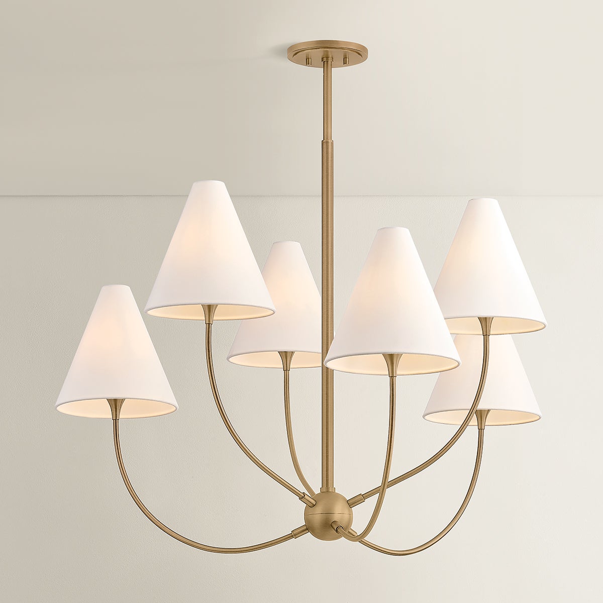 Evermore brass chandelier with six white linen shades on elegant curved arms.