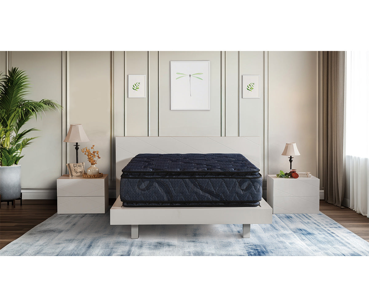 Dark blue Indulgence pillow top mattress on a modern white bed frame in a bedroom.