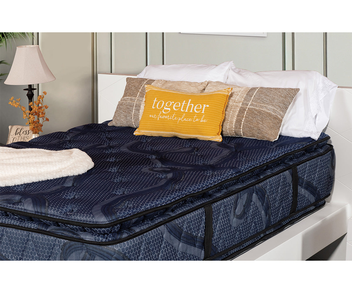 Indulgence 16-inch double-sided pillow top mattress in dark blue patterned fabric on a white bed frame.