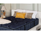 Siesta Mattress in dark blue quilted fabric with decorative pillows on a white bed frame.