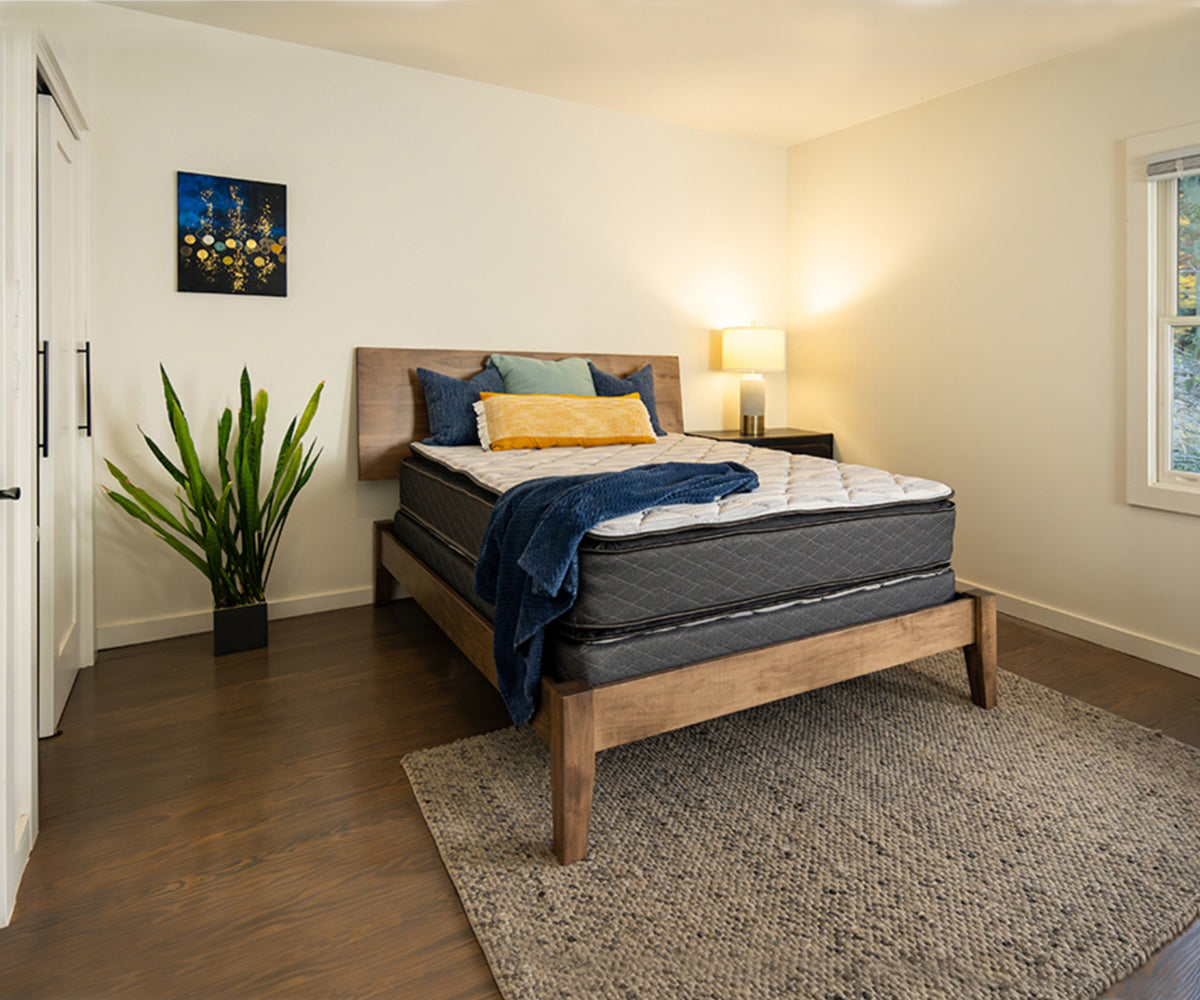 Emerald Mattress with a white quilted top and grey sides on a wooden bed frame.