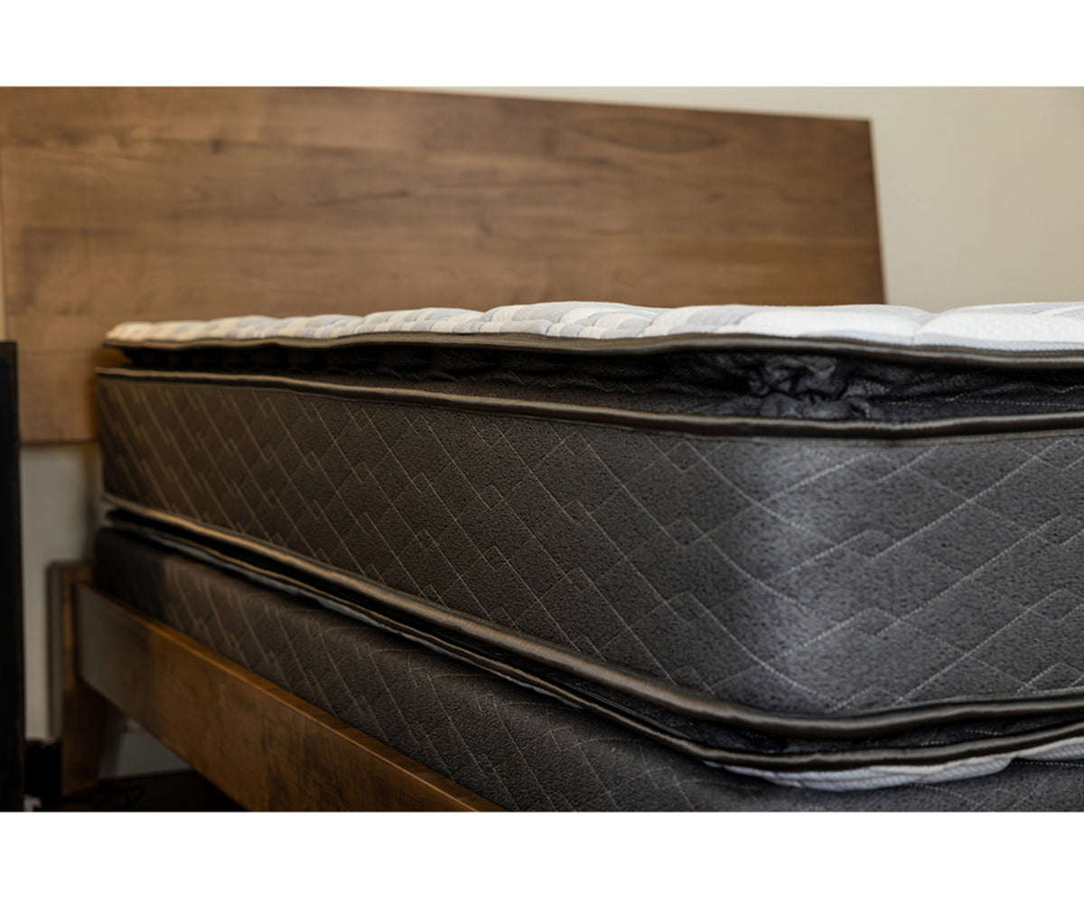 Emerald flippable mattress with dark grey quilted sides on a wooden bed frame