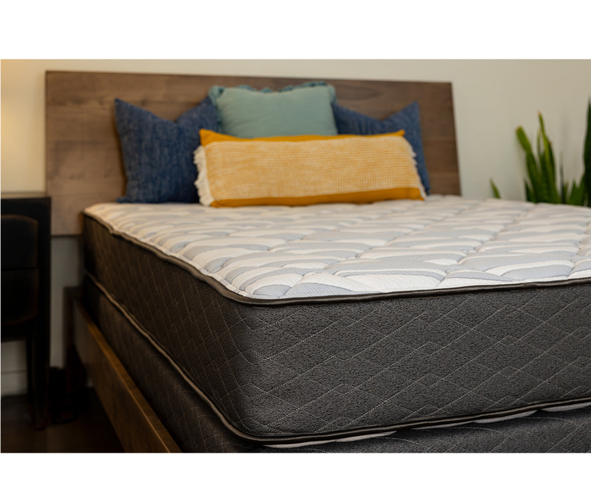 Sapphire Mattress with a quilted white top and dark grey textured sides on a wooden bed frame