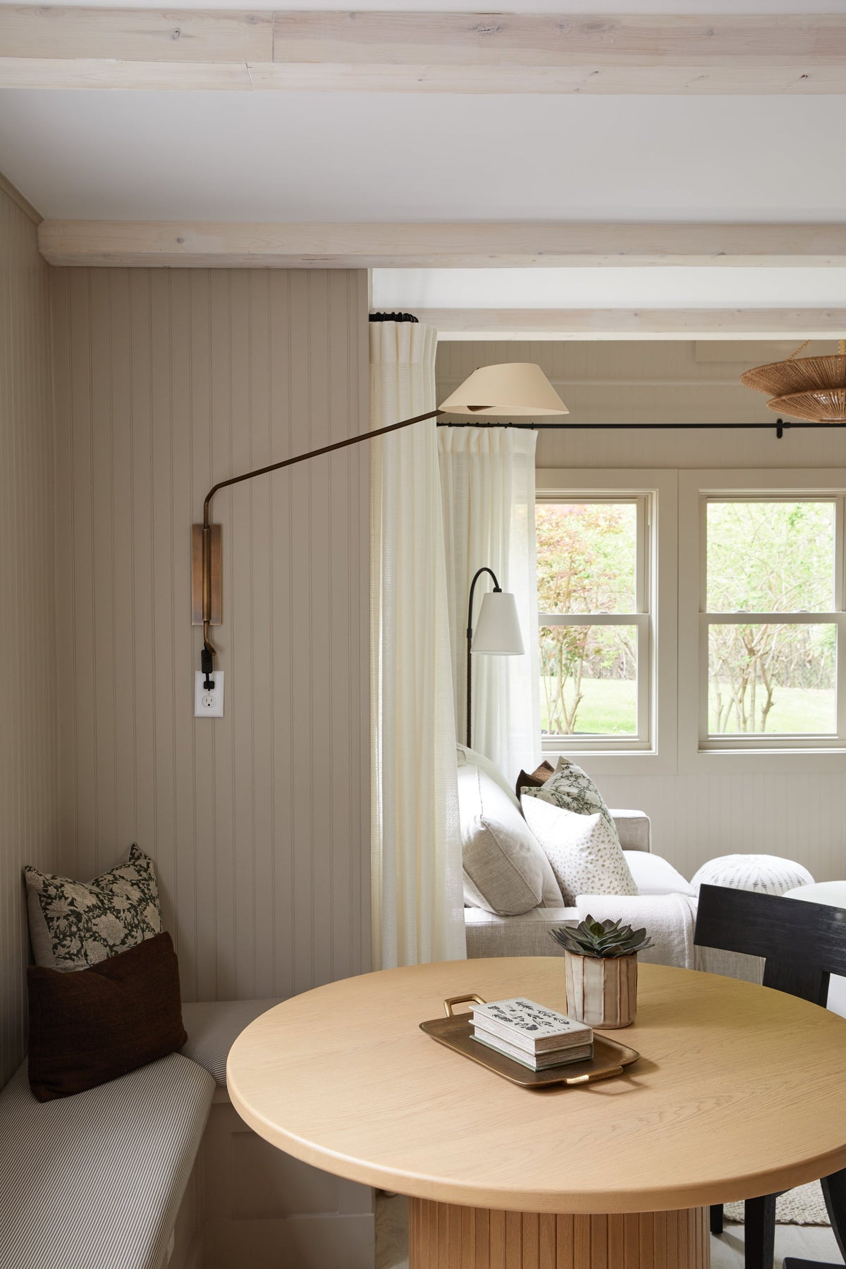 Sacramento brass plug-in sconce with a long arm and sand-colored shade mounted in a cozy dining nook