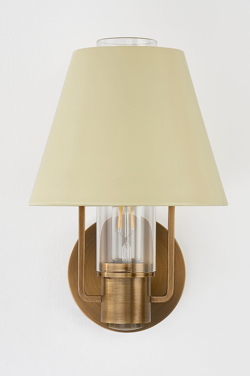 Kindle wall sconce with a soft sand tapered shade, clear glass, and patina brass metalwork.