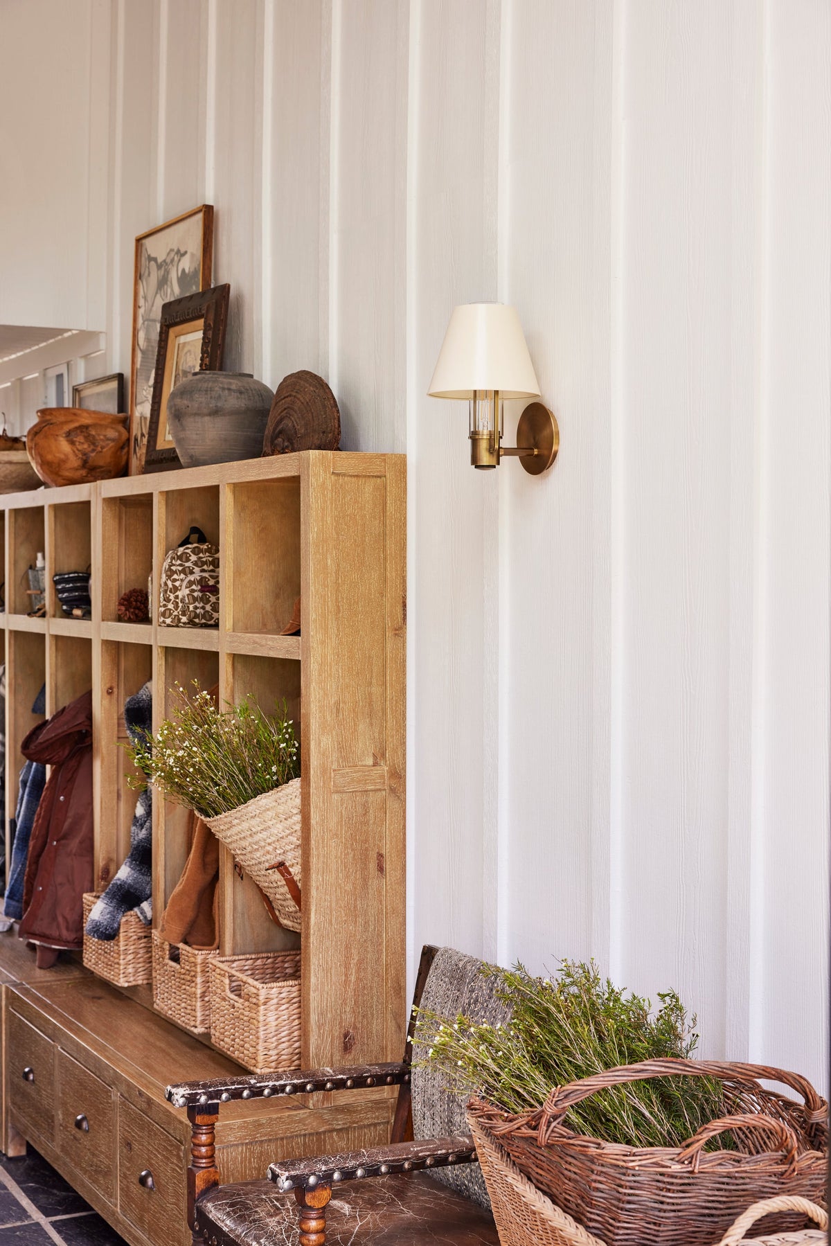 Kindle brass wall sconce with a soft sand tapered shade on a white paneled wall.