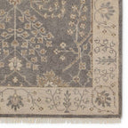 Liberty hand-knotted wool rug in muted grey and beige with traditional floral patterns and fringe.