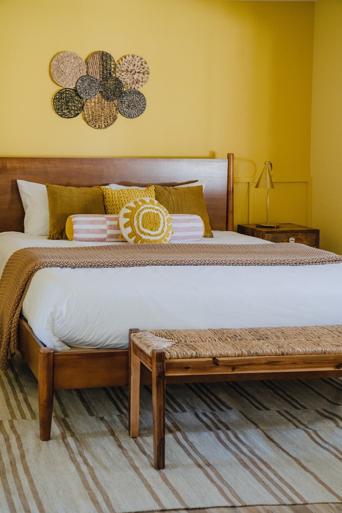 Lupe brass gooseneck table lamp on a wooden nightstand in a yellow bedroom.