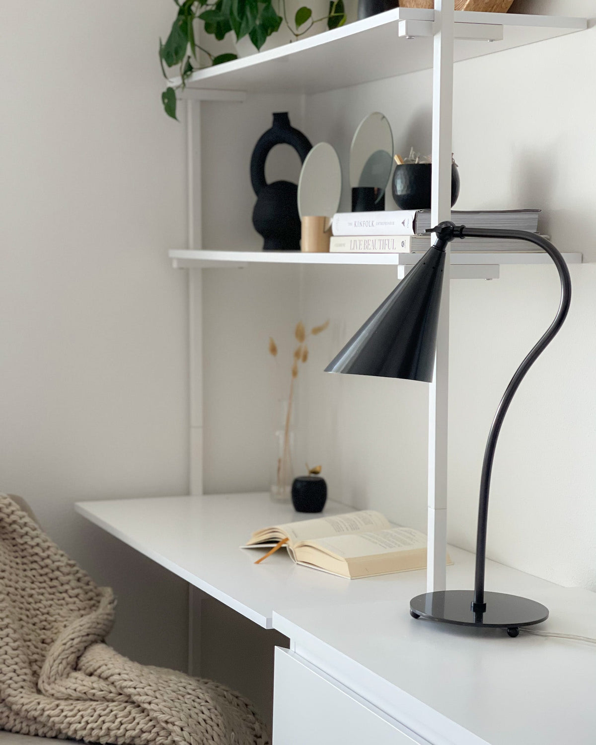 Lupe Old Bronze gooseneck table lamp with a cone shade on a white desk.