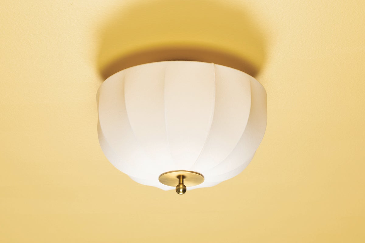 Meshelle flush mount light with a white umbrella-shaped fabric shade and aged brass finial.