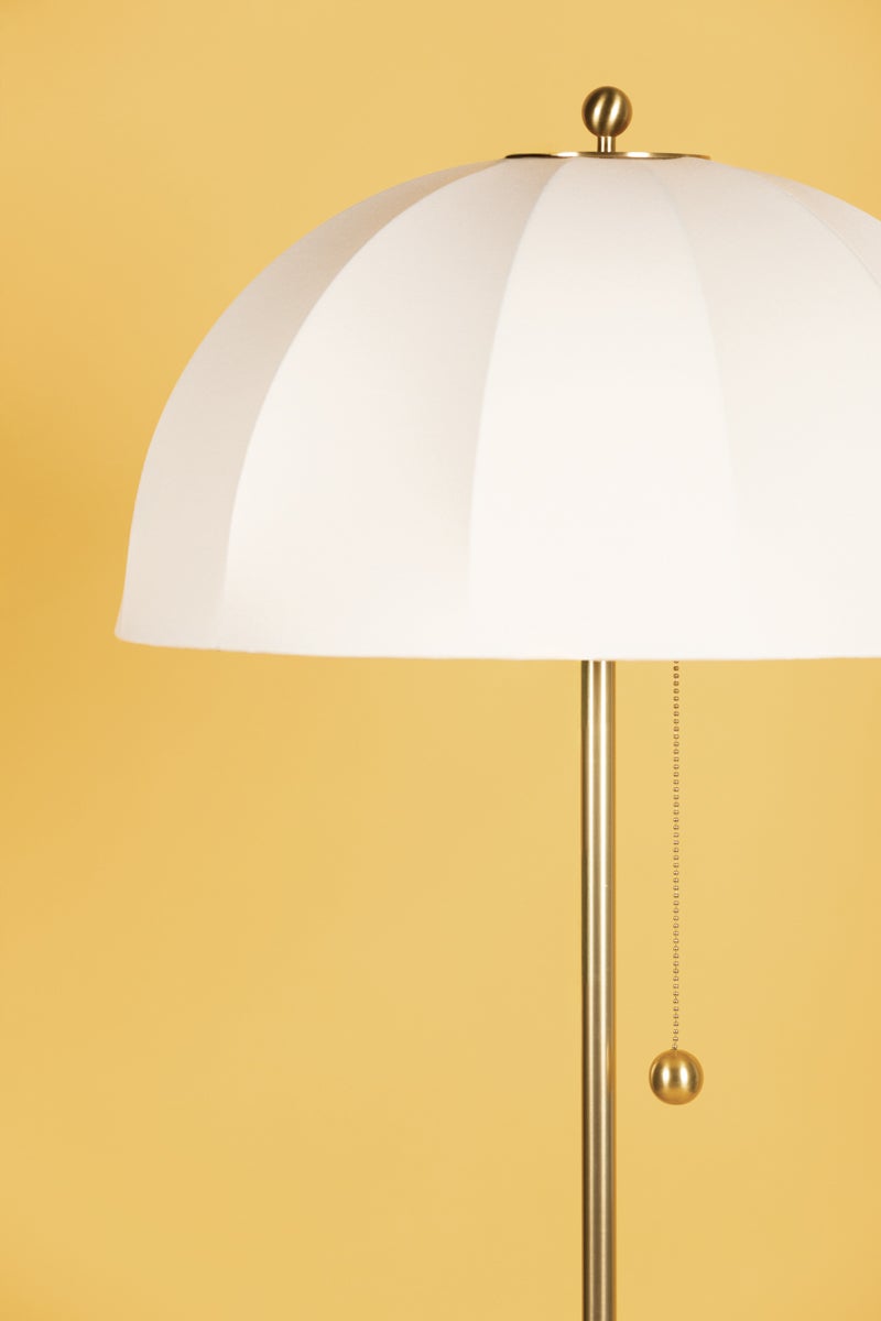 Meshelle floor lamp with a white umbrella shade and aged brass pull chain.