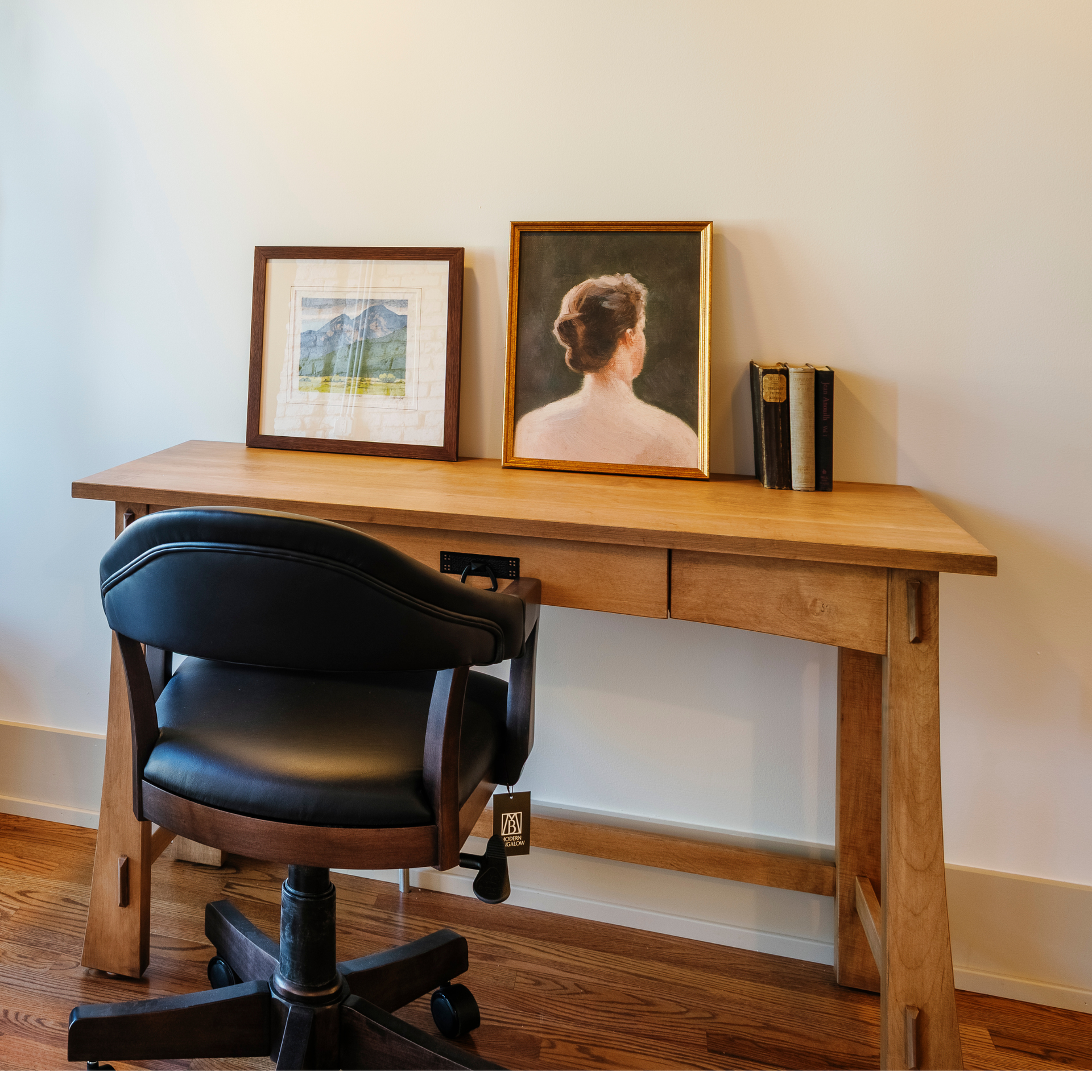 Modesto solid wood writing table with a black leather office chair and framed art.