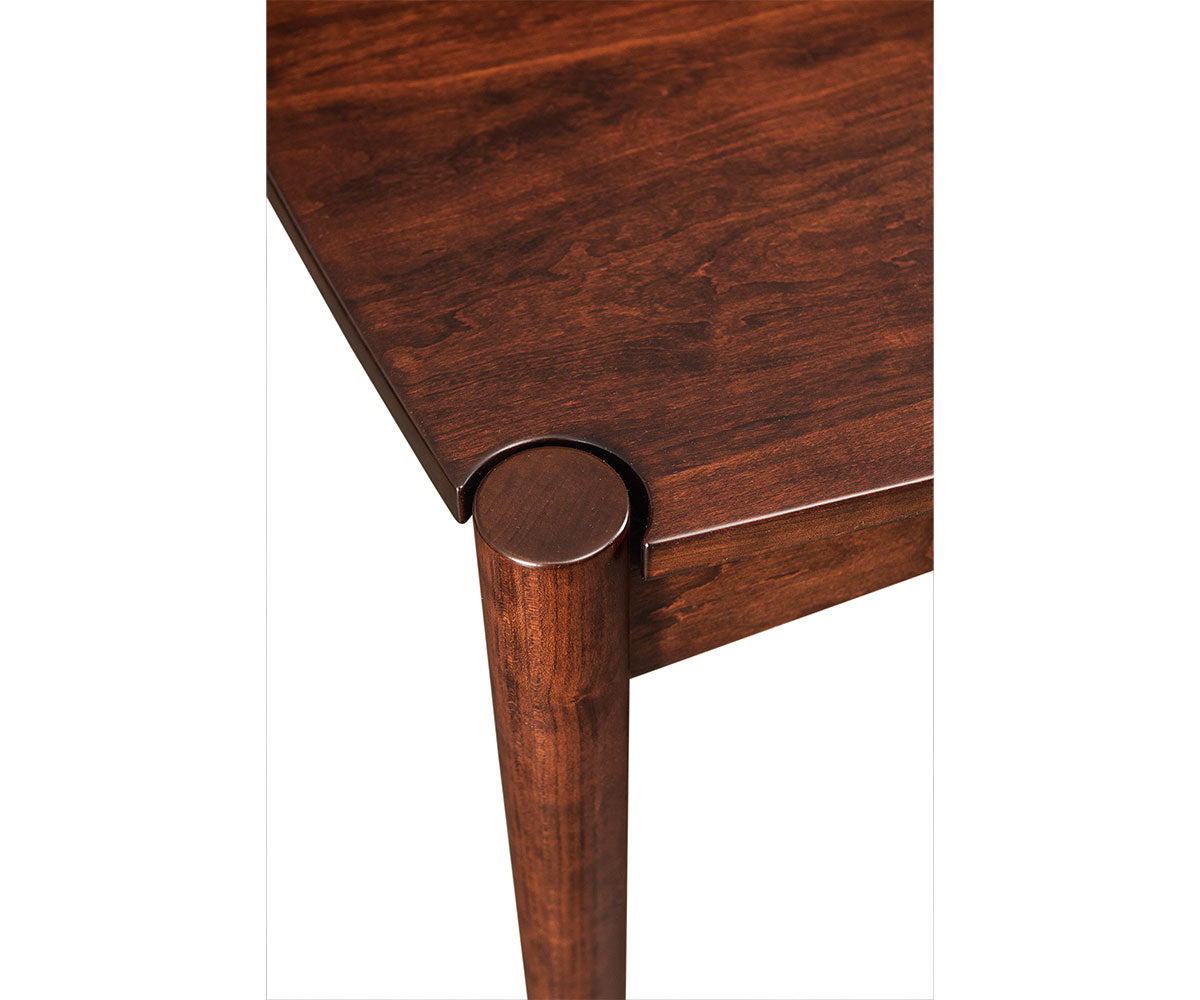 Close-up of the Wewatta solid wood dining table corner with a dark brown finish and round tapered leg.