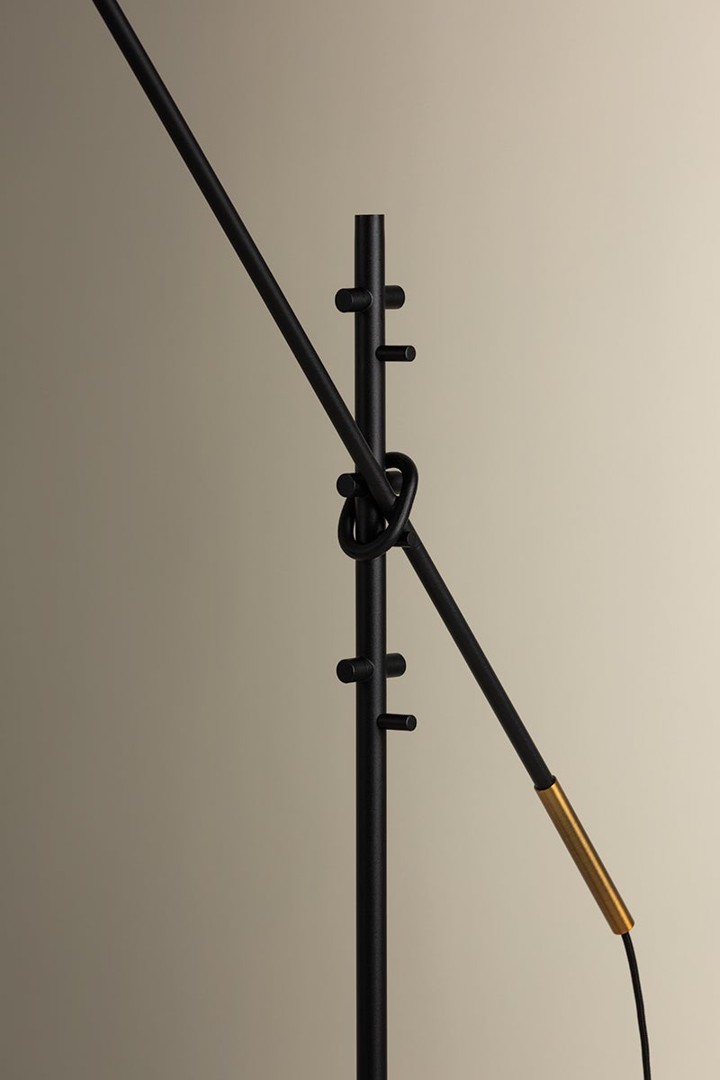 Navin floor lamp detail showing textured black adjustable arm with patina brass accent.