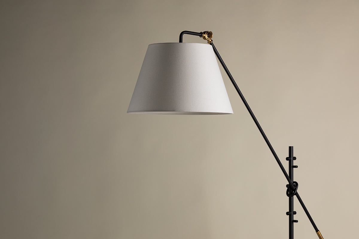 Navin floor lamp with a white linen shade, black metal arm, and brass accents.