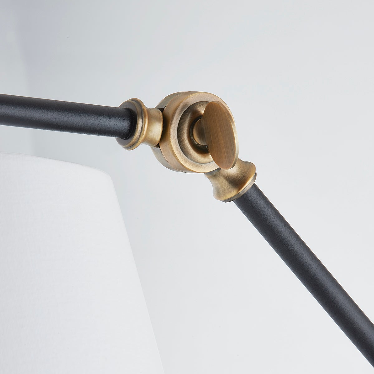 Adjustable patina brass joint on the black metal arm of the Navin sconce lamp.