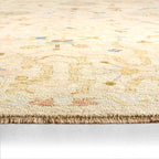 Orenda hand-knotted wool rug with muted floral patterns and fringed edge.