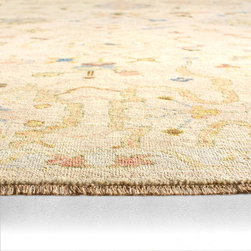 Orenda hand-knotted wool rug with muted floral patterns and fringed edge.