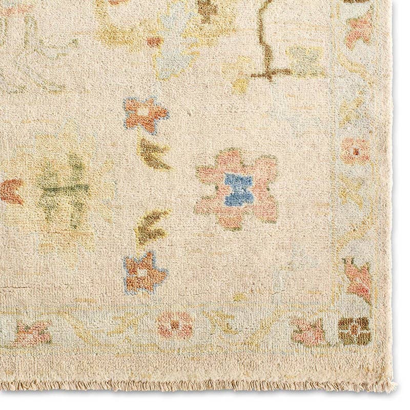 Orenda hand-knotted wool rug with muted floral patterns in cream, pink, and blue.
