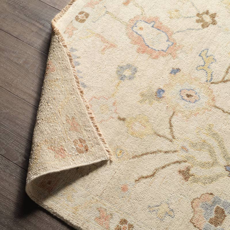 Orenda hand-knotted wool rug with muted floral patterns and folded corner showing backing.