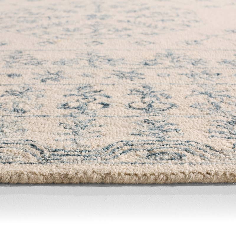 Close-up of the Province hand-tufted wool rug in cream with a blue traditional pattern.
