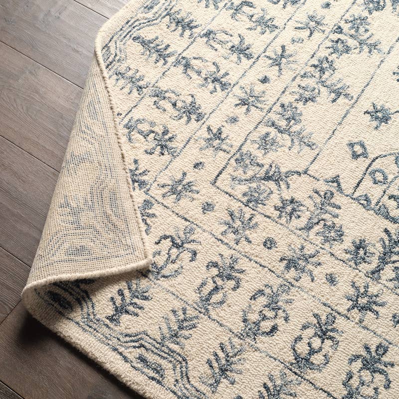 Province hand-tufted wool rug in cream and blue with a traditional pattern and folded corner.