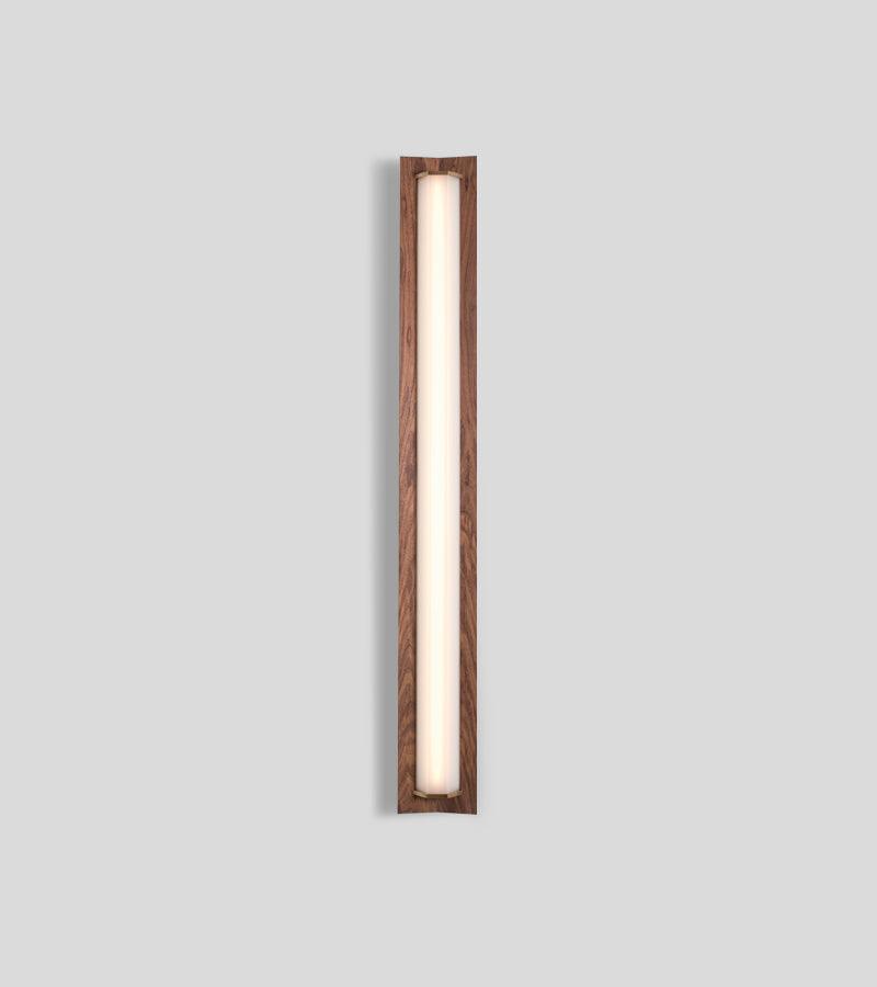 Penna Sconce in solid walnut with a glowing warm LED light panel and brass accents.