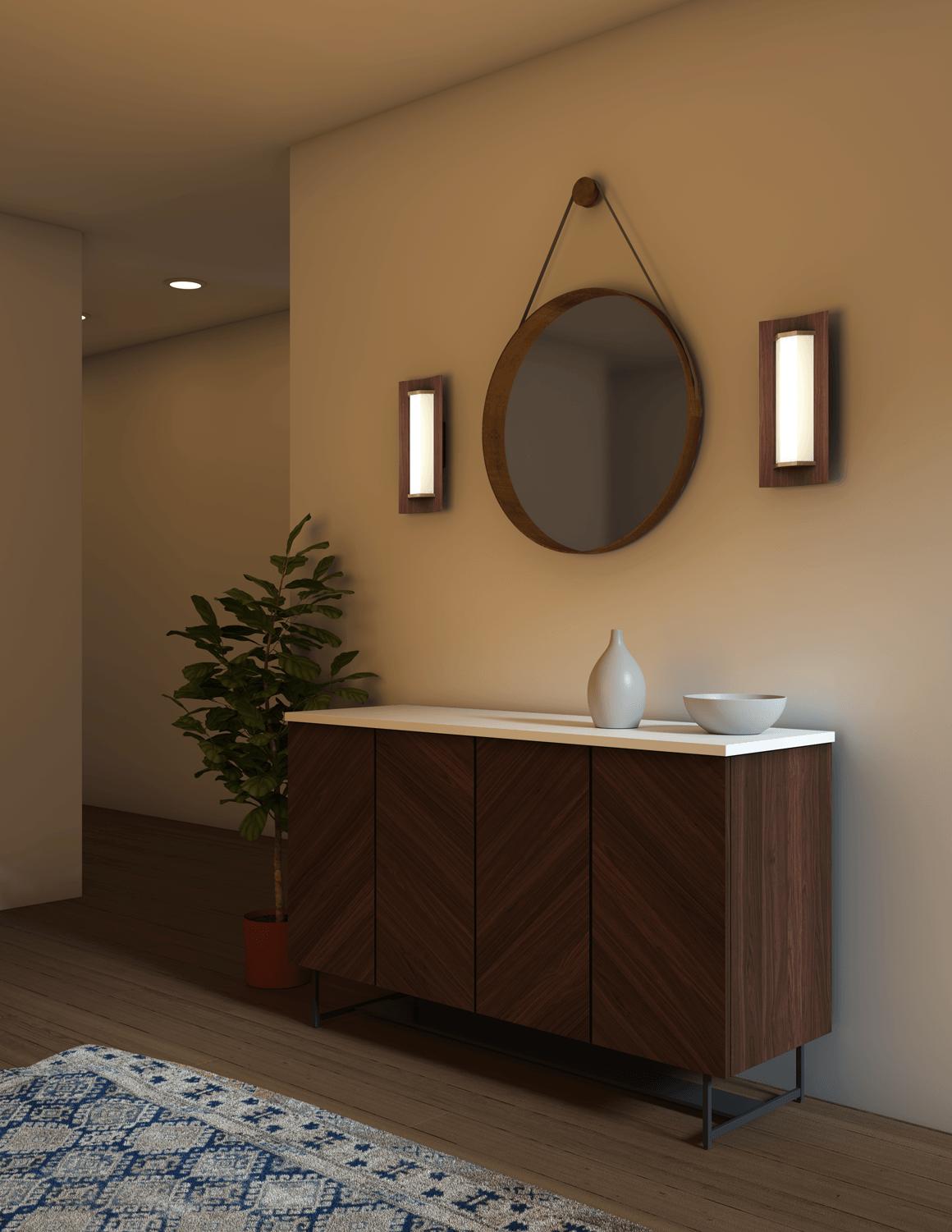 Two Penna Sconces in walnut flanking a round mirror above a wooden sideboard.