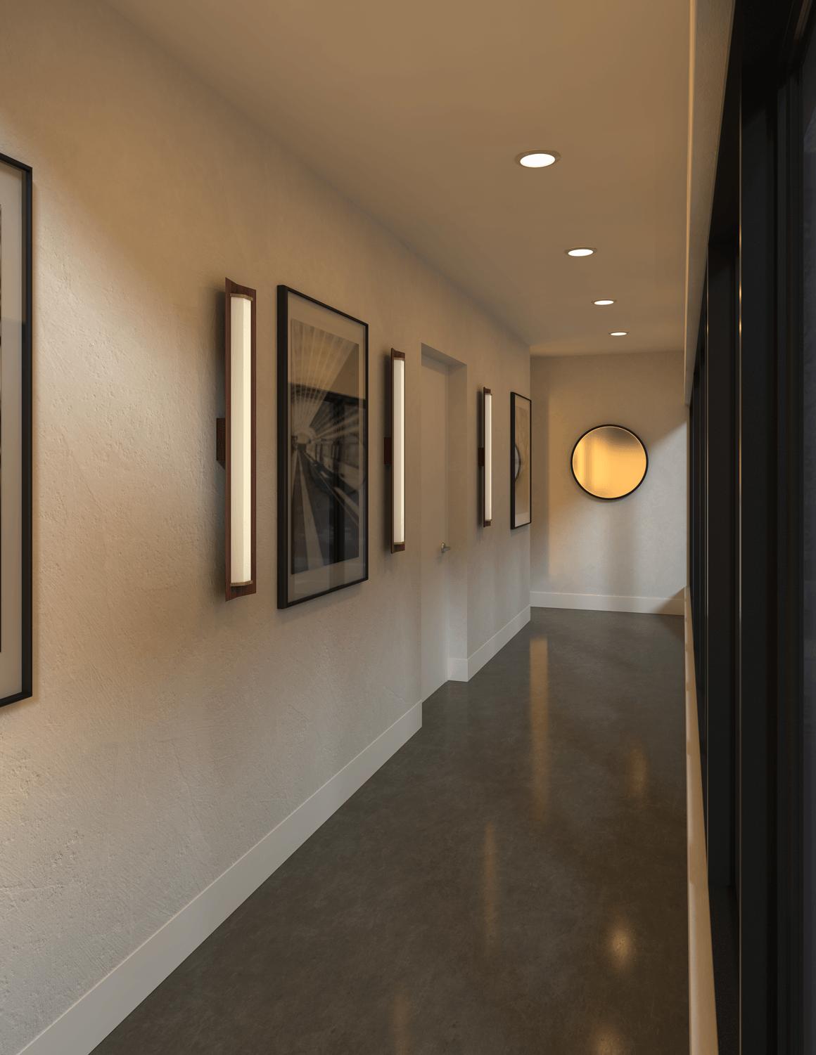 Modern Penna walnut wood and brass LED wall sconces lighting a hallway.