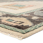 Reza hand-knotted wool rug corner with muted blue, cream, and pink geometric patterns and fringe.