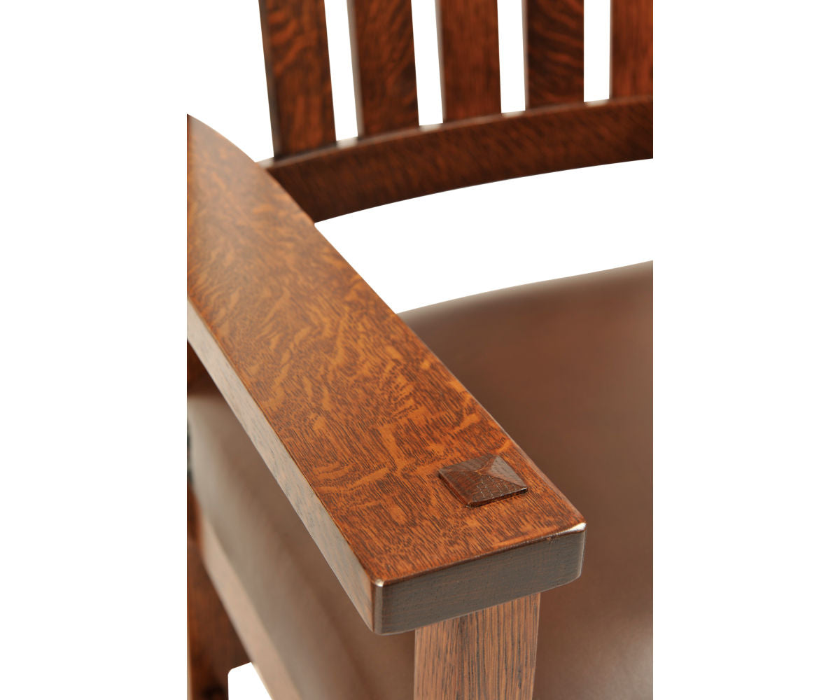 Conner Craftsman arm chair in dark brown oak wood with a leather seat and exposed joinery.